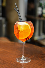 Closeup glass of spritz aperol cocktail decorated with orange at bright bar counter background.