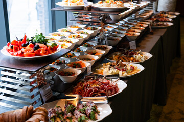 A variety of fresh dishes displayed on a buffet table at a catered event, featuring salads, appetizers, and hot meals arranged in a professional food service setup