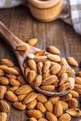 Almond kernel nuts on spoon on wooden table.