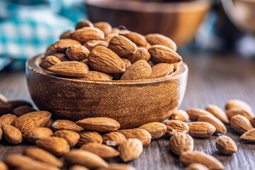 Almond kernel nuts in bowl on wooden table.