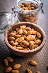 Almond kernel nuts in bowl on wooden table.