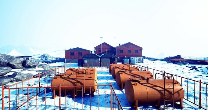 Bright orange tanks stand in stark contrast to the icy landscape, framing a remote research facility nestled among snow covered peaks, signifying human resilience in harsh environments.