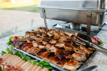 Grilled meat served on a tray at a festive outdoor gathering during bright daylight