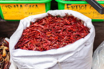 A close-up image showing a bag filled with dried red chili peppers at a market