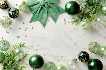 Elegant green Christmas balls and bow frame on white marble background.