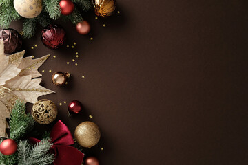 Elegant Christmas background with gold and red baubles, fir branches, poinsettia flower on brown...