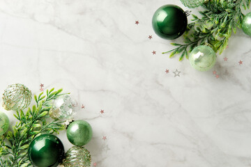 Two corner frame of green Christmas baubles and spruce branches on marble background