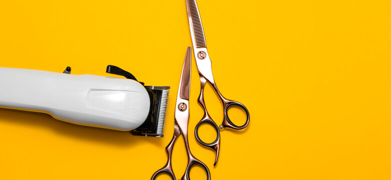 Hairdressing and barber tools. Professional scissors and hairdressing clipper. Bright yellow background. The concept of hair care and professional grooming. Copy space for marketing materials. - Powered by Adobe