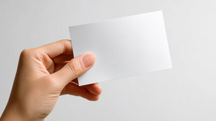 Obraz premium Blank card held in hand against a plain background