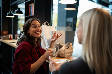 Happy women friends conversing and laughing in cafe