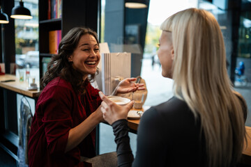 Women friends laughing enjoying coffee conversation in cafe