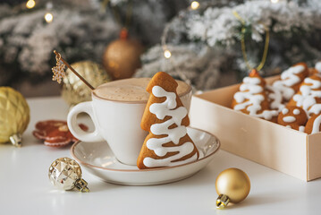 Cup of Hot Coffee with Christmas Gingerbread tree-shaped Cookies and Ornaments in Festive Setting
