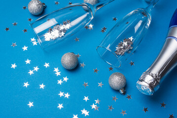 Champagne Bottle and Flutes with Silver Ornaments for New Year Celebration on Blue Background © thayra83