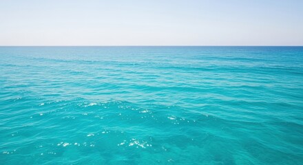 Vast expanse of clear turquoise ocean water stretching towards a bright cloudless horizon under a pale sky