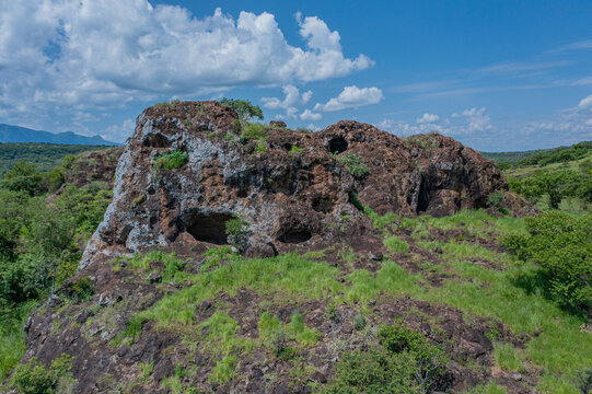 Aerial view of the Napedet cave and sparse vegetation against a backdrop of a clear blue sky, Pian Upe Game Reserve, Moroto, Uganda.