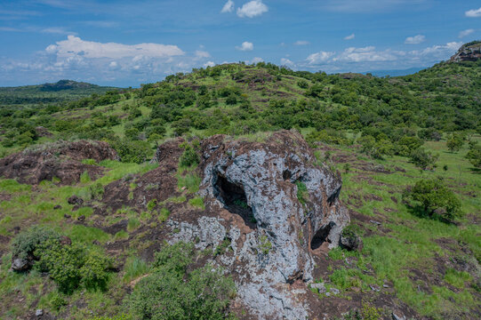 Aerial view of the Napedet cave where rocky outcrops meet verdant plains under a vast sky, Pian Upe Game Reserve, Moroto, Uganda.