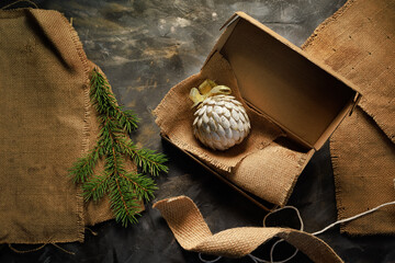 Simple eco kraft box made from recycled materials holds a valuable holiday gift on rustic fabric and a dark surface.Concept of meaningful gifting, sustainable packaging, emotional branding.