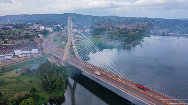 Aerial view of the Jinja Nile Bridge with its cable stayed design reflecting in the water under a cloudy sky, Jinja Nile Bridge, Eastern Region, Uganda.