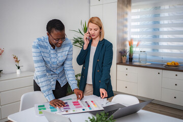 Businesswomen collaborating on design while talking on phone call