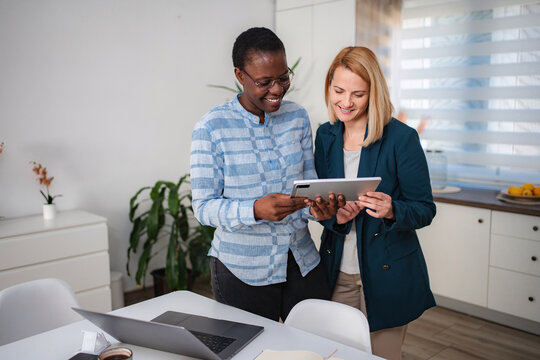Two businesswomen collaborating on digital tablet in modern office - Powered by Adobe