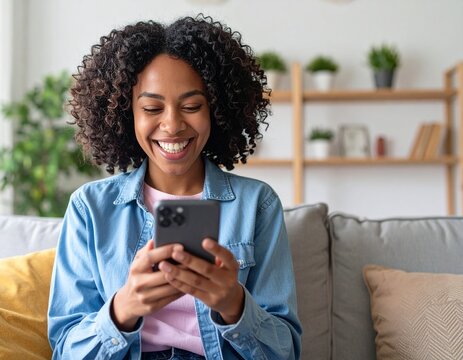 A smiling young adult Gen Z woman of Asian descent is captured in her cozy living room, sitting on a sofa and relaxing. She is intently focused on her mobile phone, engaging with a dating app. Her ple