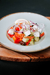 Colorful salad with fresh vegetables and herbs served on a wooden board in a stylish dish