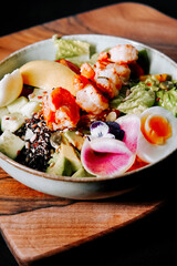 Fresh and colorful shrimp salad served in a bowl on a wooden platter