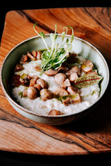 Delicious bowl of creamy mushroom and grain dish served on rustic wooden board