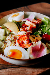Colorful shrimp salad bowl with fresh vegetables and eggs at a cozy dining setting
