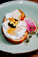 Delicious open-faced sandwich with cheese, flowers, and fresh toppings served on a green plate