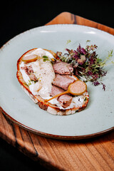 Unique open-faced sandwich with meat and sauce served on a rustic plate