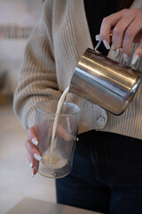 Women pour hot milk in glass.