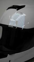 Close-up of a white and black motorcycle helmet with a reflective sticker, showcasing safety gear.
