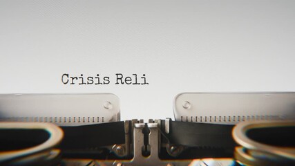 Old mechanical typewriter typing Crisis Relief Fund in a close-up view, with metal letters striking the white paper.