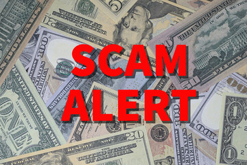 Background of US currency overlaid with words SCAM ALERT in red