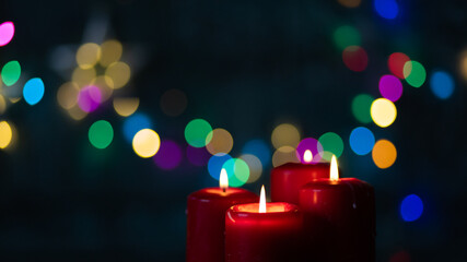 candles burning against holiday lights background