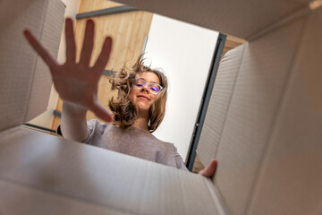 Teen girl over box, wide inside perspective and gentle focus. Inside view.