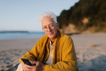 Elderly caucasian male enjoying a beach sunset with smartphone