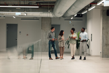 Diverse business people walking talking in modern office corridor