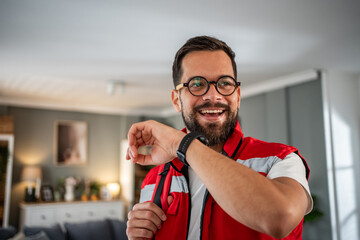 Smiling paramedic man checking smartwatch at home