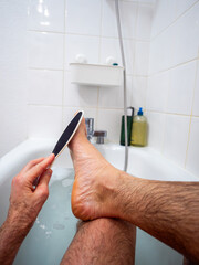 Home pedicure in the bathtub with heel file