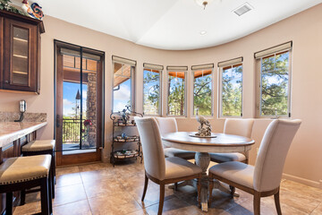 A spacious dining room with a table and chairs, lit by windows