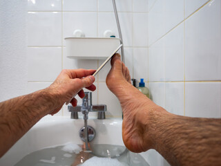 Home pedicure in the bathtub with heel file