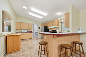 A kitchen that features a bar area complete with stools in it