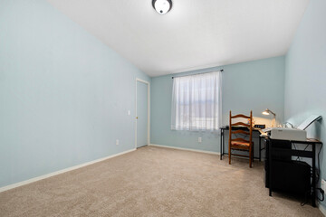 An empty bedroom that features a desk along with a chair in it