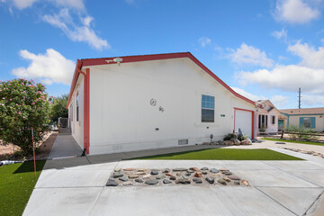 A white house with red trim and a sturdy concrete driveway