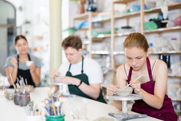 Students teenage girl and teenage boy sculpt ceramic product from raw clay in workshop