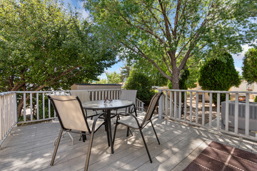 A deck with a table and chairs, surrounded by lush trees