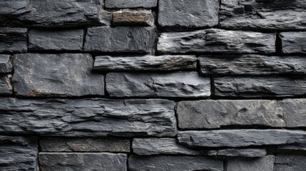 Layers of dark stone create a textured wall with varying shapes and tones ideal for modern decor.