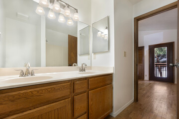 Spacious bathroom with two sinks, a large mirror, and wooden cabinets